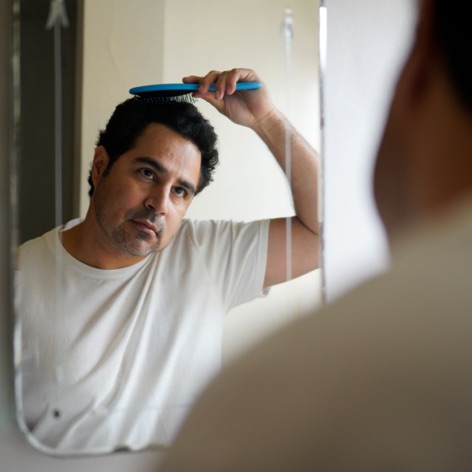 Man brushing his hair while looking in the mirror