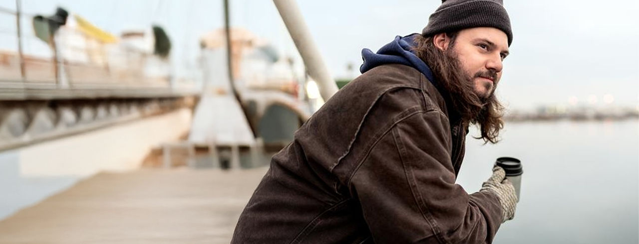 Man in commercial fishing boat, drinking coffee while leaning on the gunwale