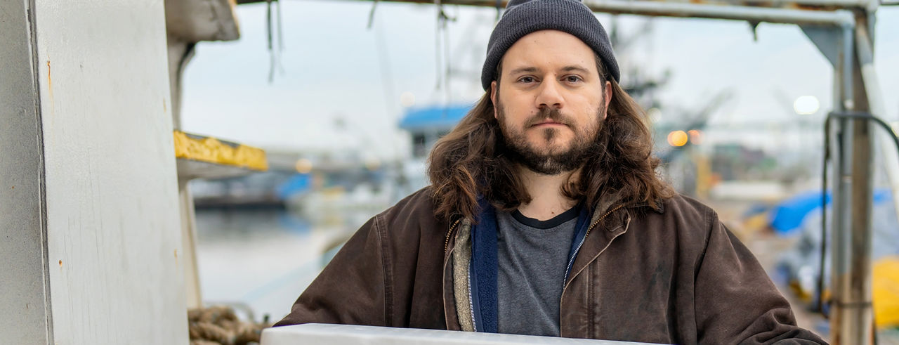 Man standing outside by a fishing boat